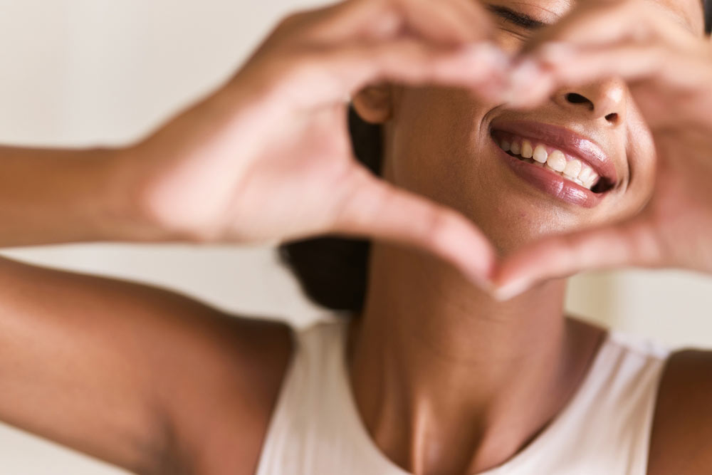 Woman Making a Heart Shape with Her Hands, Emphasizing Happiness, Positivity, and Oral Health.