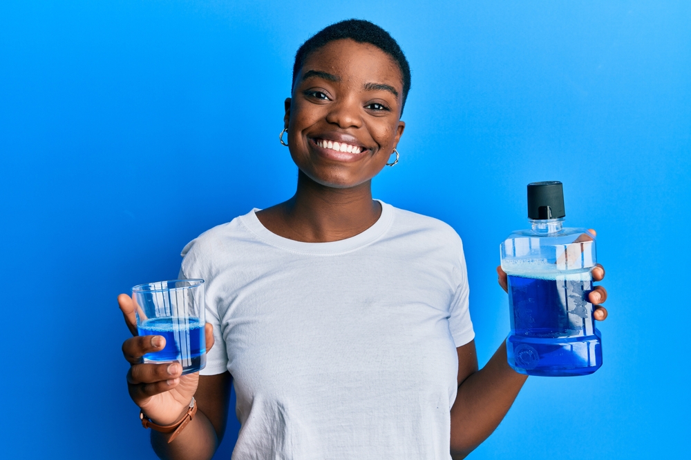 Young african american woman holding mouthwash for fresh breath