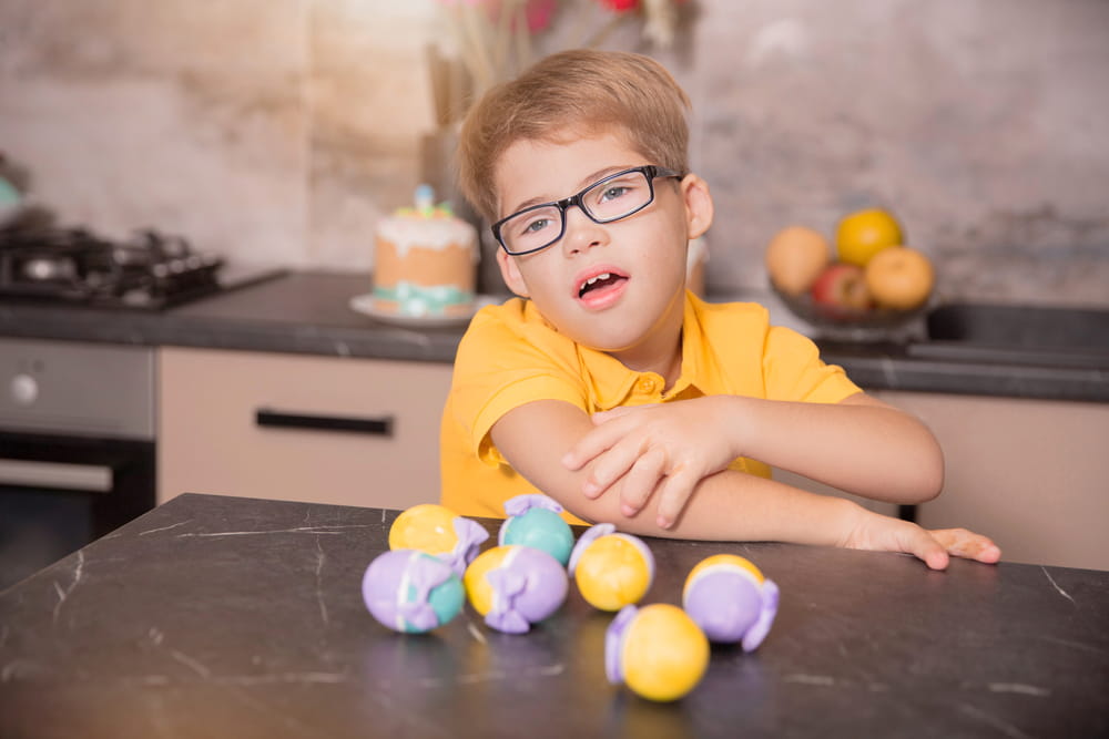 Portrait of a boy with Down syndrome with Easter decor. Colorful eggs and cakes.