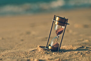 Hourglass on a sand dune beach. (vintage style)