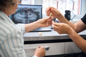 Doctor shows a model of a dental implant to patient