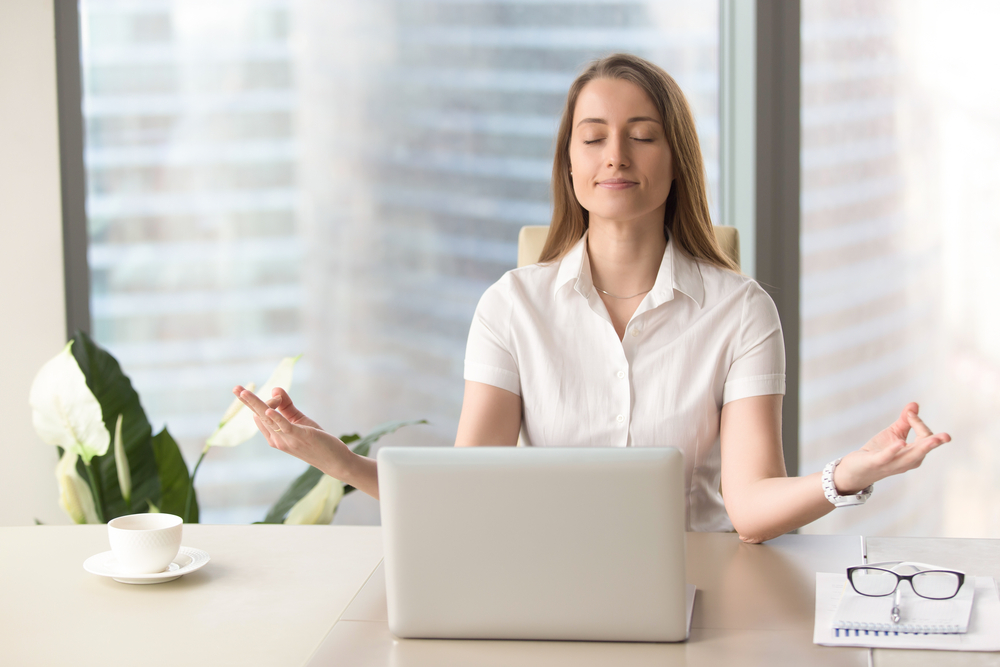 Mindful businesswoman practices breathing exercises at workplace