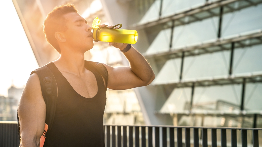 Fitness, black man and drinking water in city with fatigue, break and relax for exercise recovery