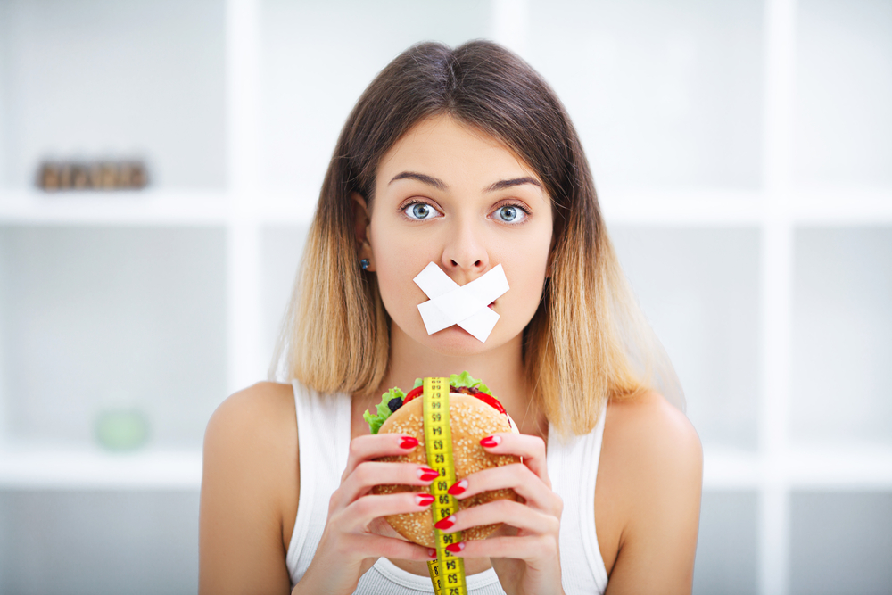 Diet. Portrait woman wants to eat a Burger but stuck skochem mouth