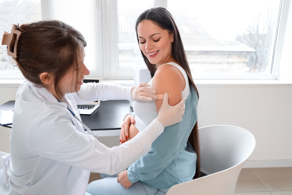 Young pregnant woman receiving medical patch after vaccination at hospital