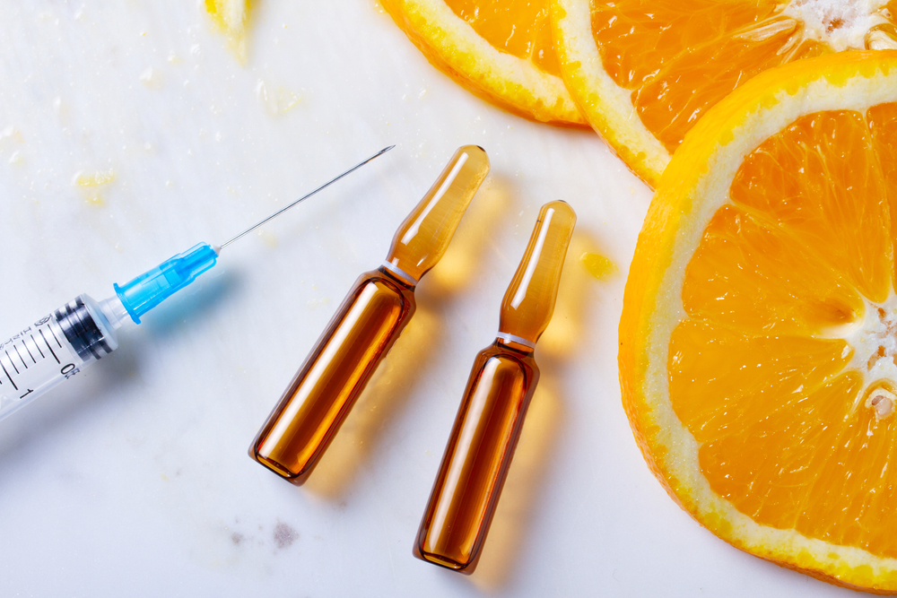 Vitamin C, natural anti aging cosmetics serum and syringe with ornge fruit slices