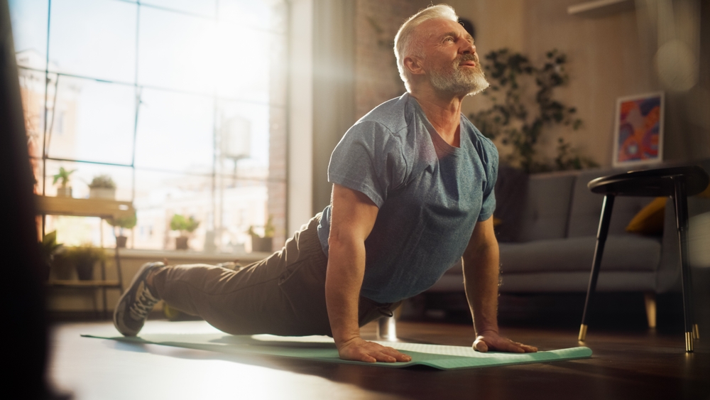Strong Athletic Fit Senior Man Training on a Yoga Mat,