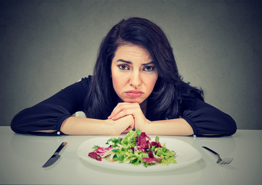 Dieting habits changes. Sad woman hates vegetarian diet