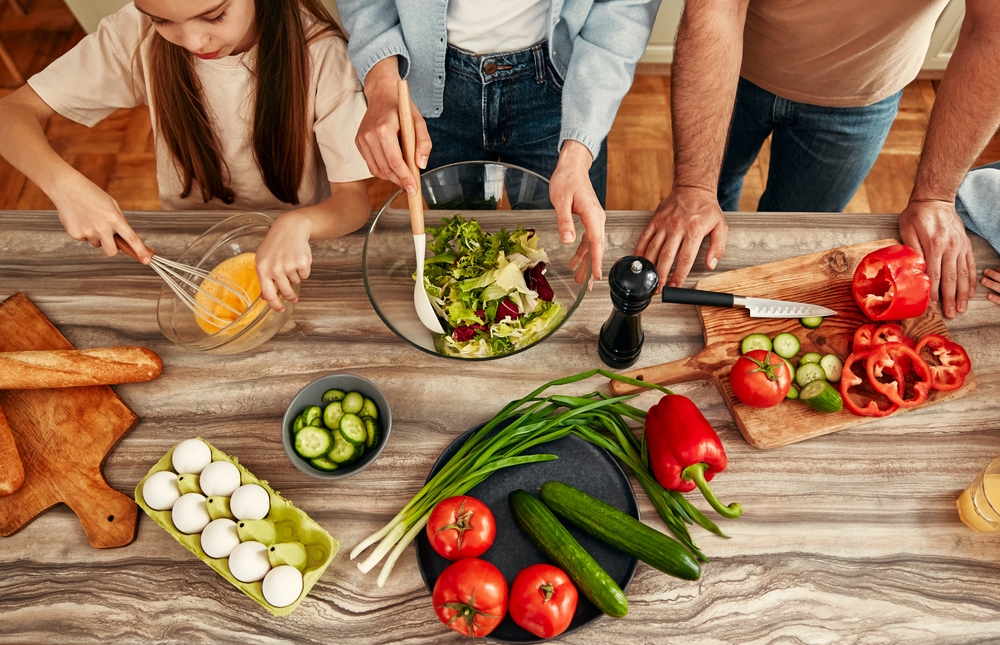a family comes together to bond and prepare a healthy salad using fresh vegetables,