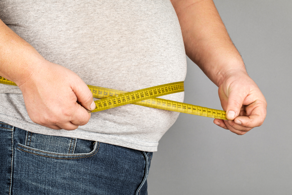 A man measures his fat belly with a measuring tape