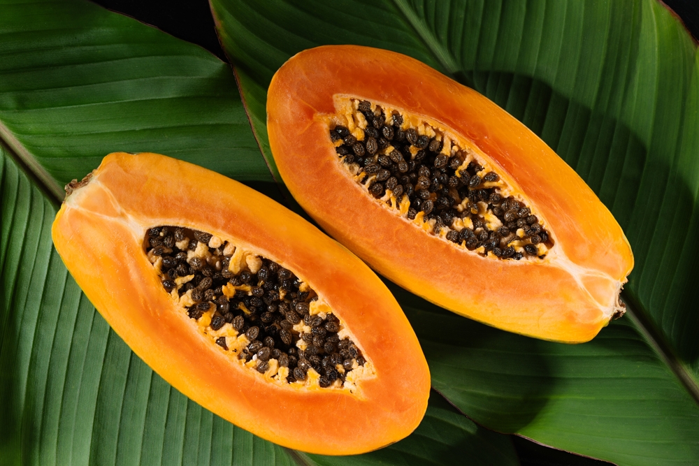 papaya fruit cut in half, with seeds and bright orange flesh