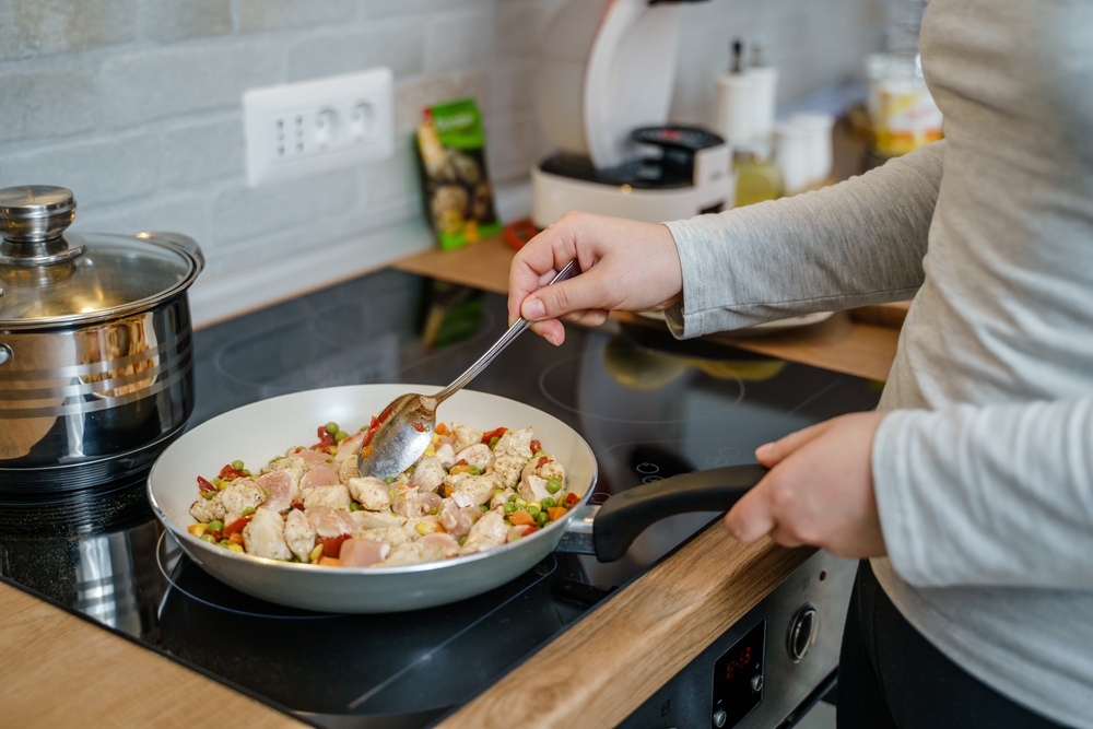 woman with cooking pan making vegan or vegetarian healthy meal at home