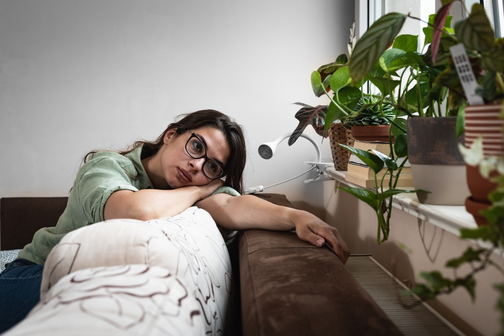 Young sad woman with broken heart sitting alone at home suffering from depression anxiety