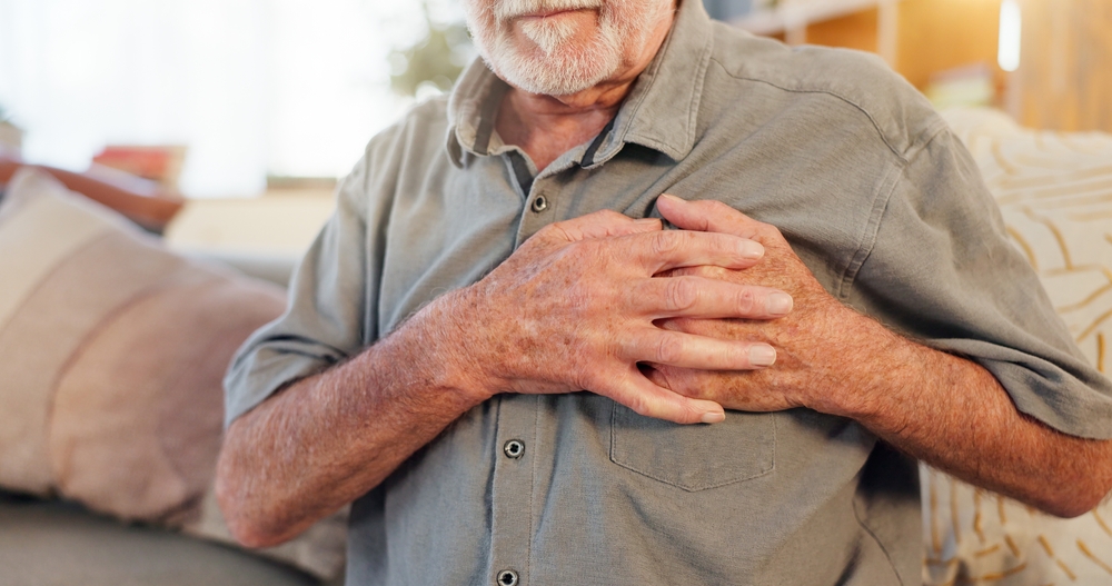 Old man, home and hands on chest for heart attack, pain and hypertension stress or lung fail.