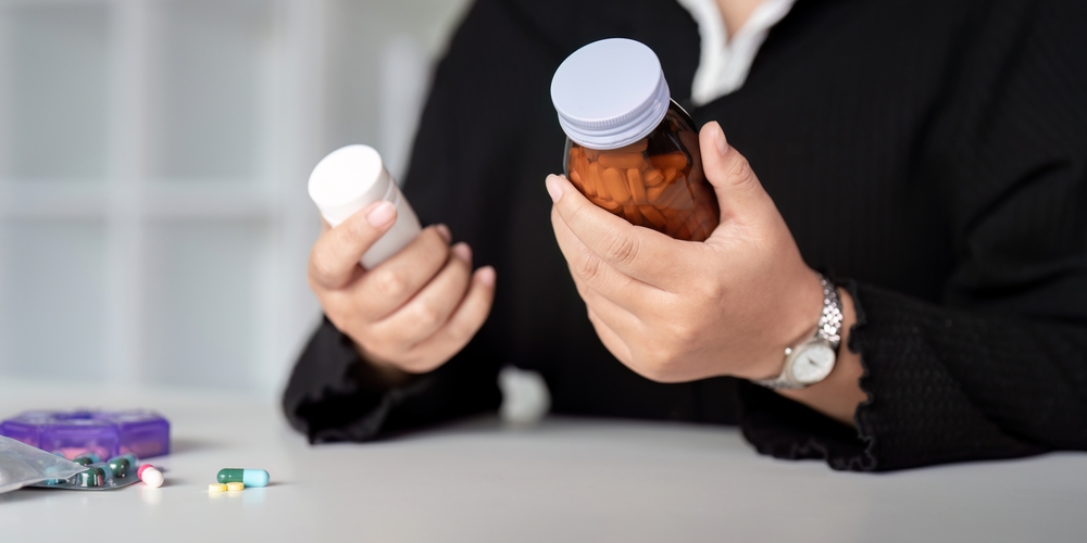 Close up woman holding pill in hand with water.