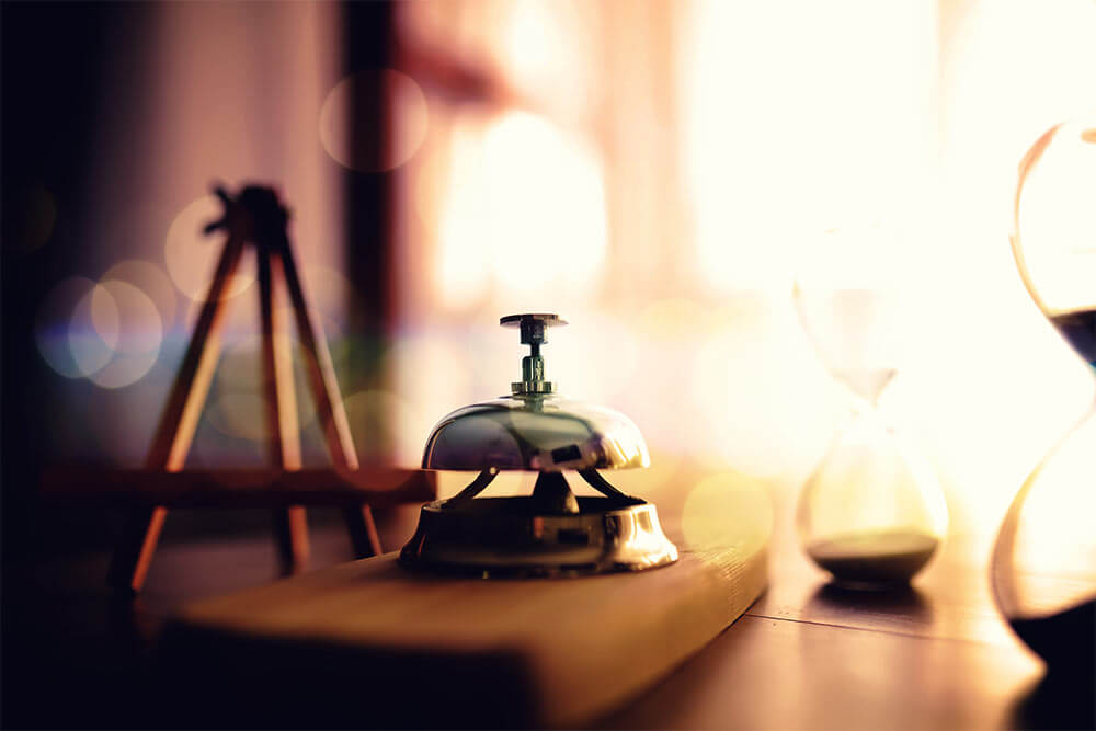 Hotel service bell on wooden reception desk.