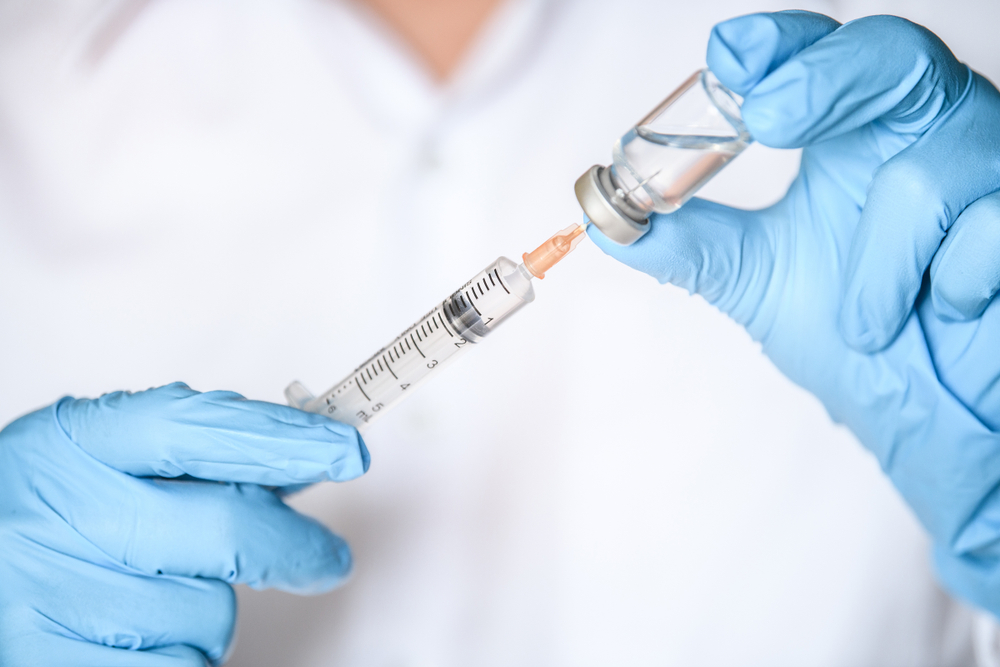 Doctor, nurse, scientist hand in blue gloves holding flu, measles, coronavirus, covid-19 vaccine
