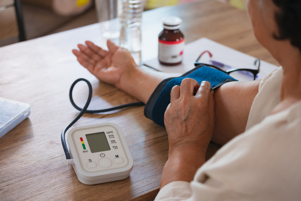Senior woman is checking blood pressure and heart rate with digital pressure gauge by herself at home