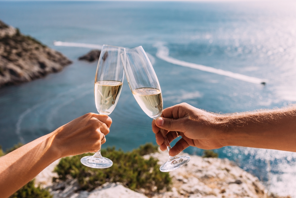 Hands holding champagne glasses over the sea