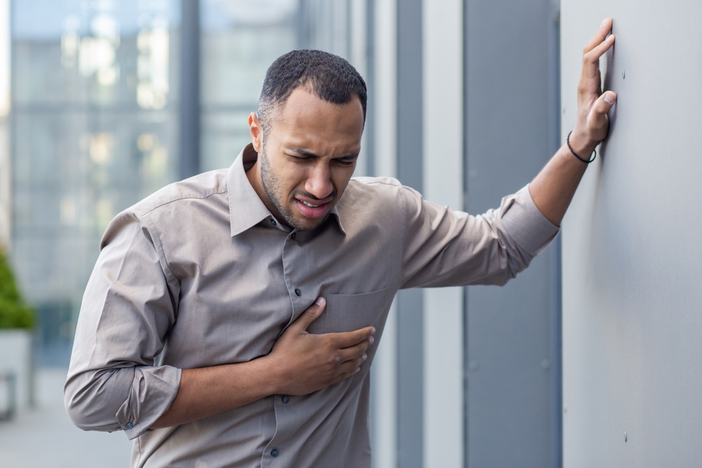 Man experiencing chest pain outdoors, clutching his heart in distress,