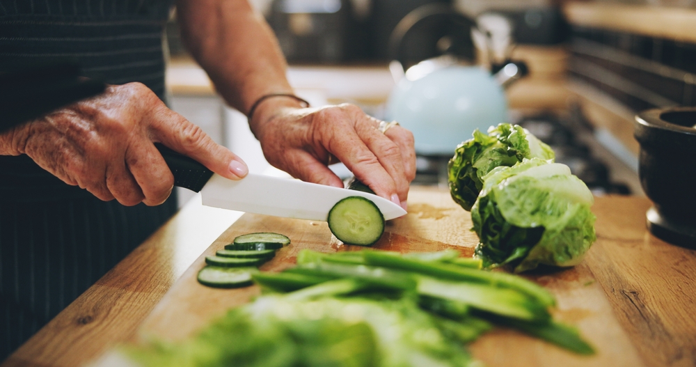 Hands, cutting board and salad in kitchen with green vegetables for healthy food