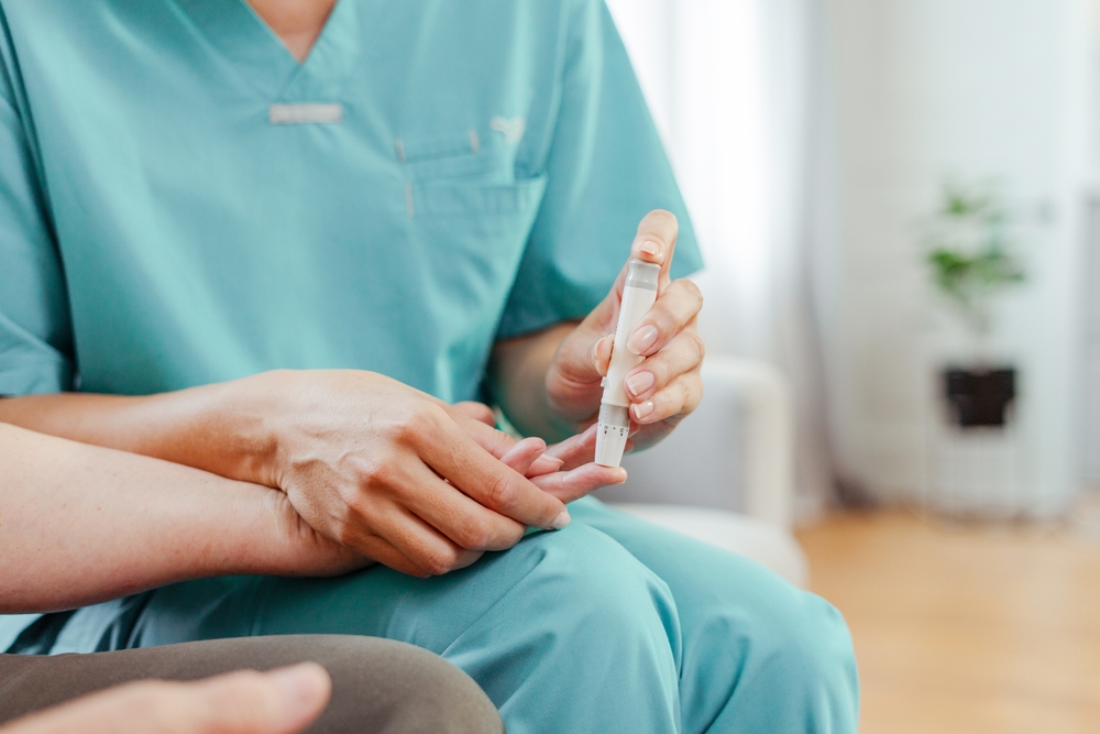 Nurse checks an elderly patient's blood sugar with a lancet pen