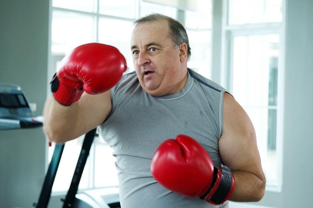 An overweight man wearing boxing gloves exercising