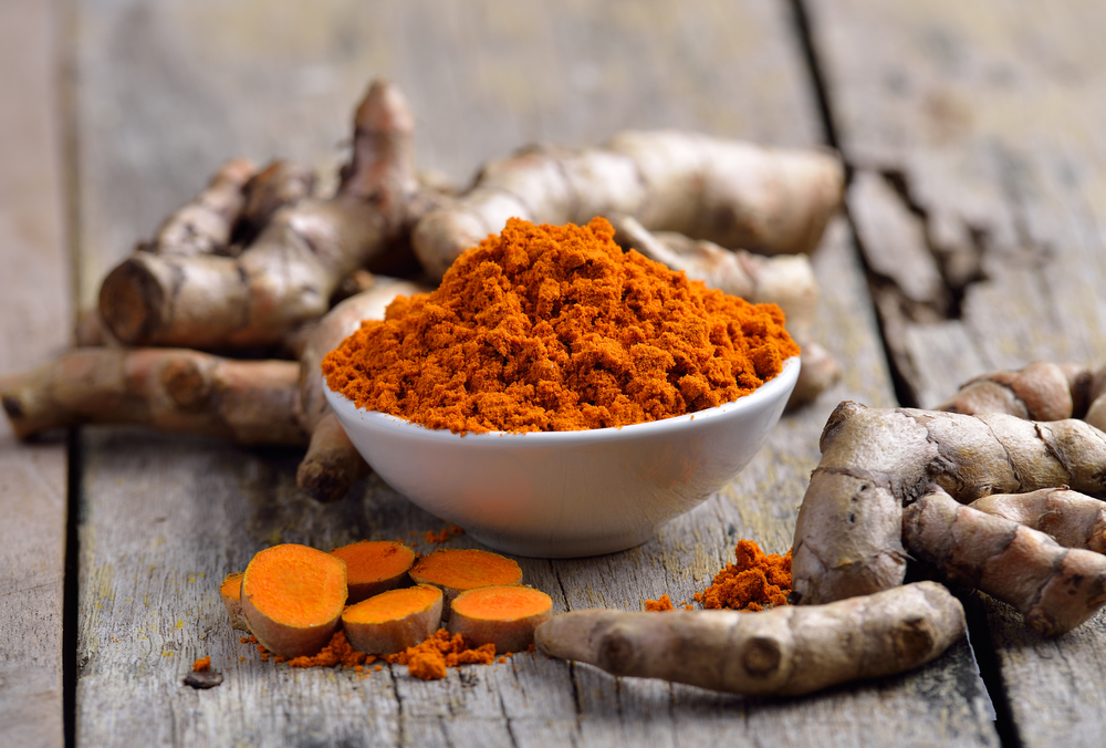 fresh turmeric roots on wooden table