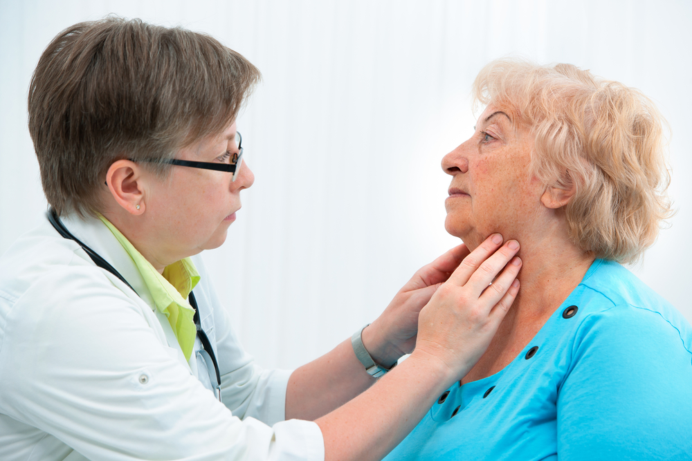 Thyroid function examination. Doctor touching the throat of a patient in the office