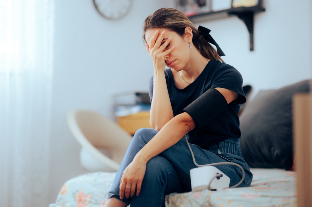 Woman Taking her Blood Pressure feeling nauseated and ill