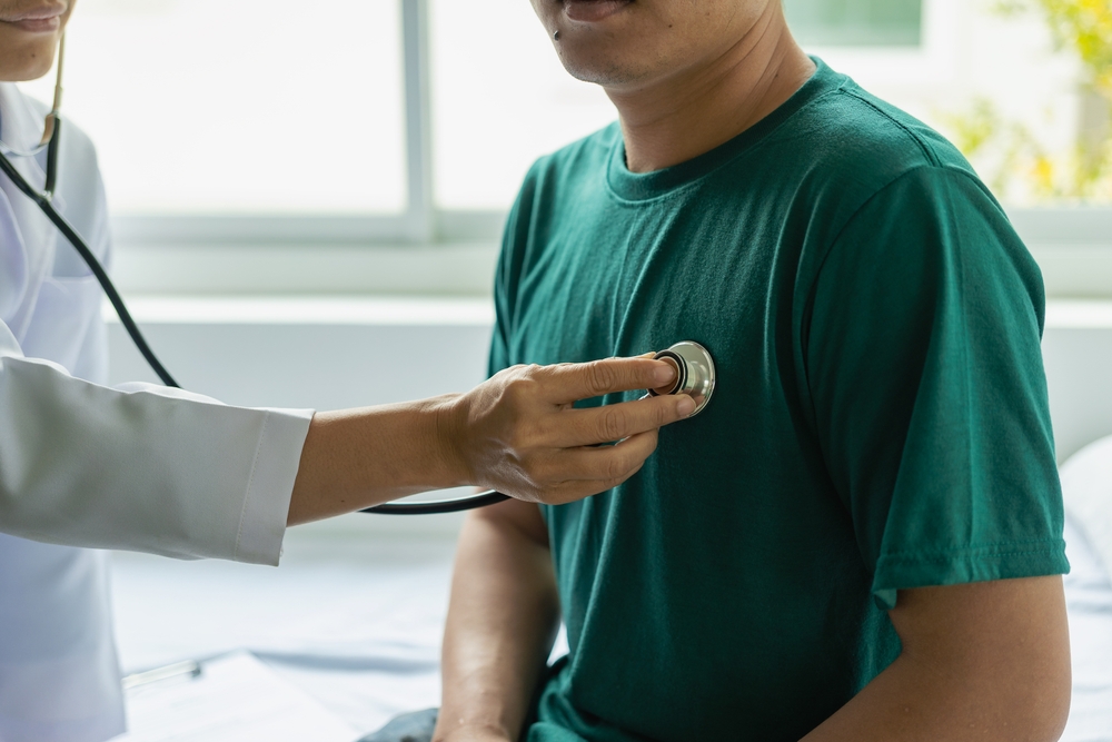 Doctor uses stethoscope to diagnose heart on patient in exam room at hospital, physical exam, medicine