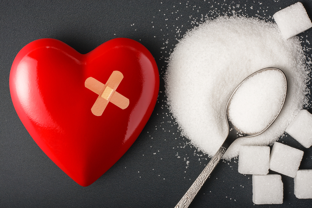 Unhealthy food concept - sugar. Spoon with sugar and heart with bandage