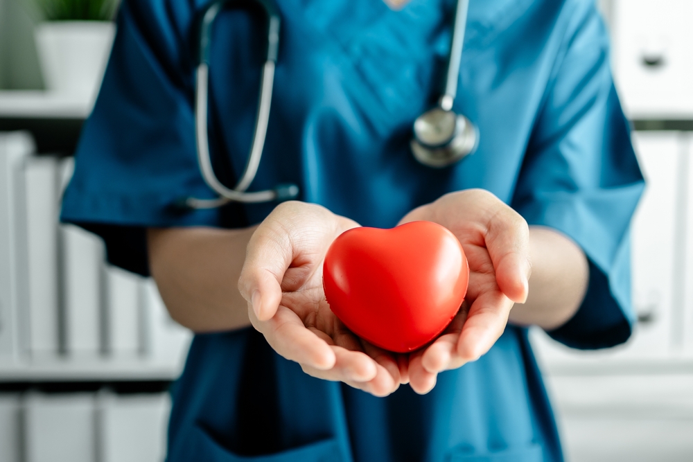 Medicine doctor woman holding a red heart, showing, cardiograph, promoting medical insurance, early checkup