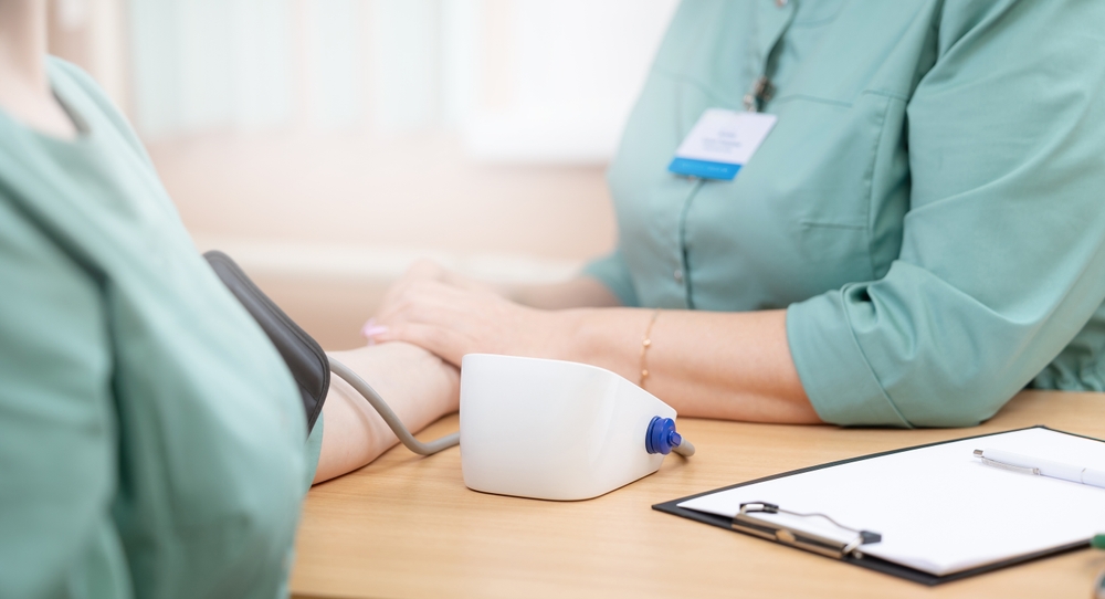 Healthcare professional checks blood pressure of female patient in medical office, banner.
