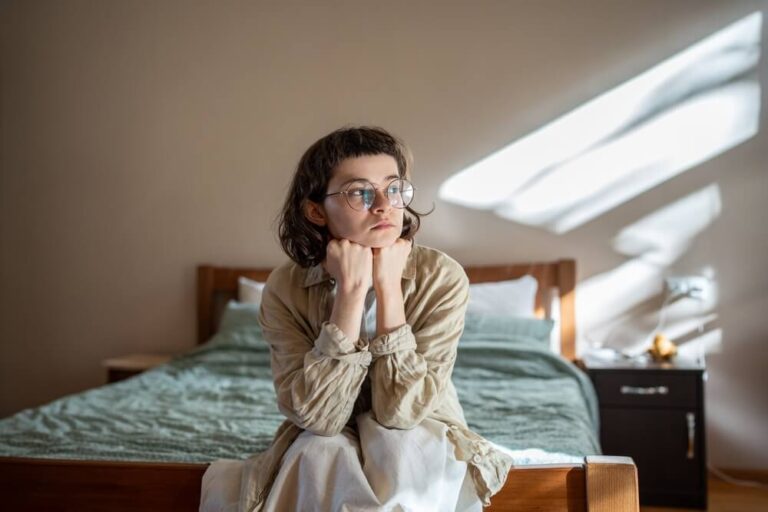 Depressed lonely woman sitting on cozy bed