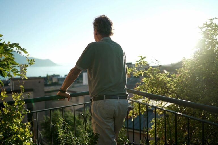 Older man standing outdoors looking at view from home