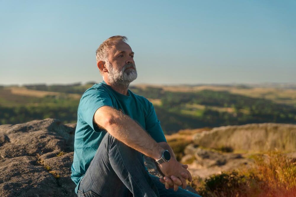 Older Man Contemplating Scenic View on Rocky Hilltop