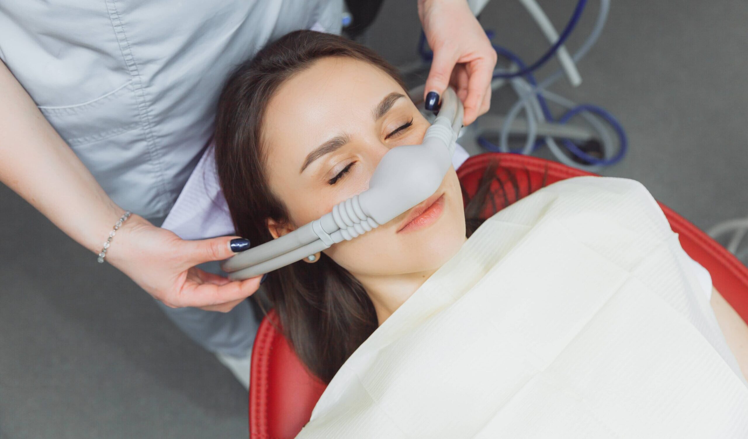 dentist puts inhalation sedative mask on his patient.