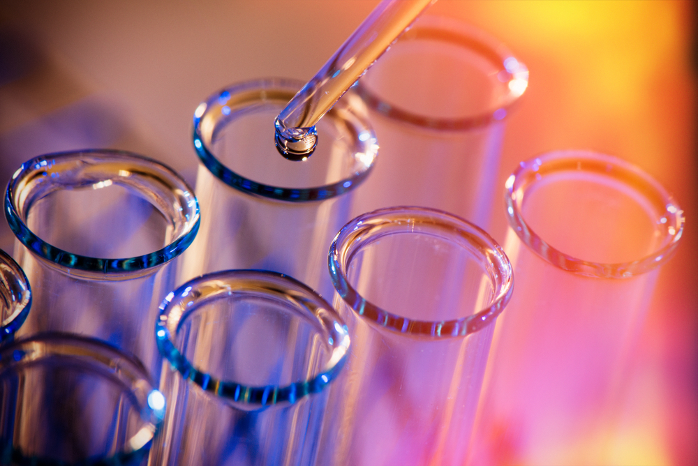 a liquid is being transferred using a dropper into test tubes