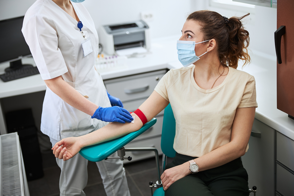 A female patient wearing a medical mask being prepared for venipuncture