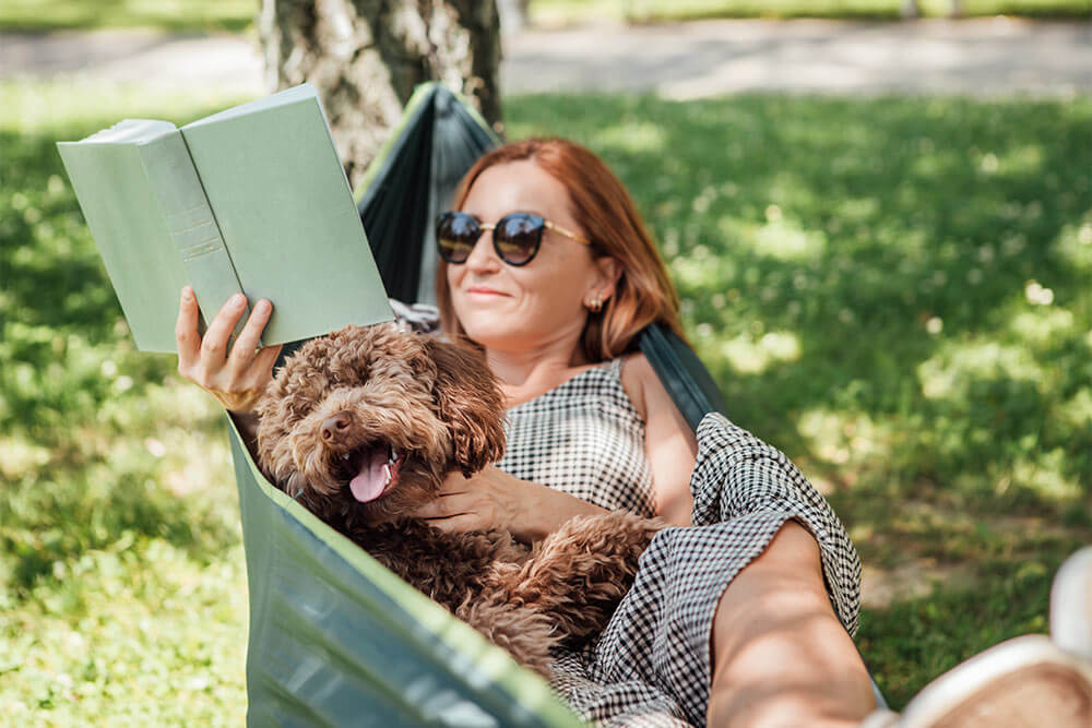woman reading book with a dog