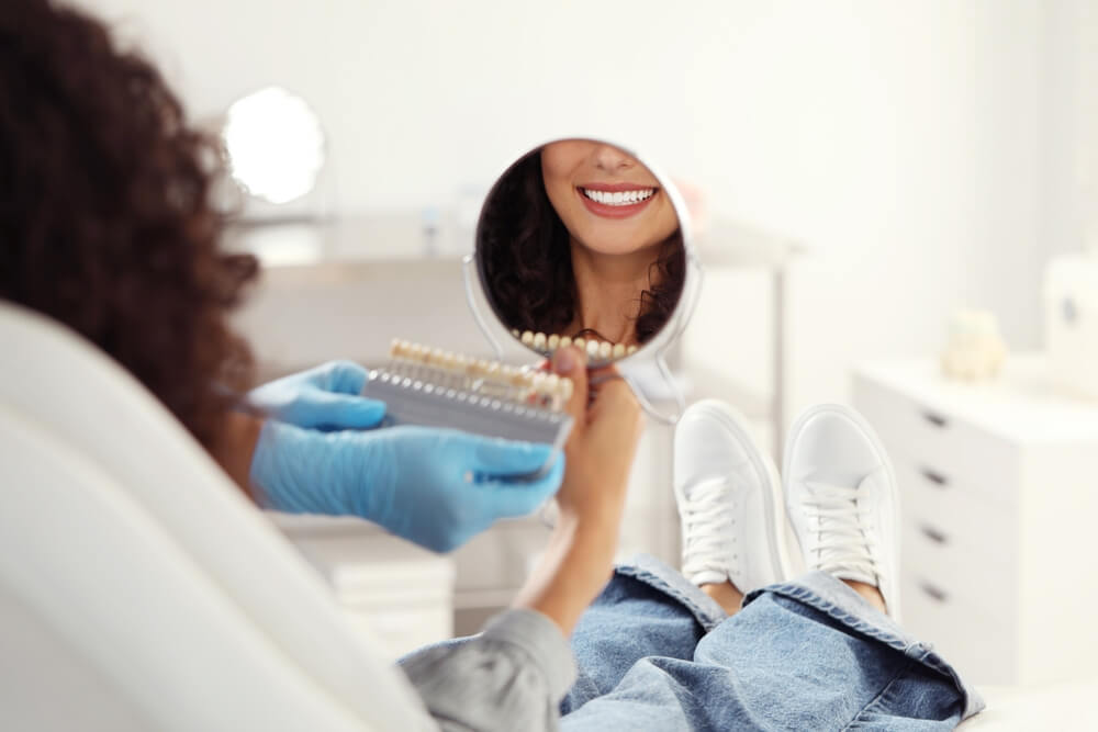 Patient looking in mirror while doctor holding teeth color chart