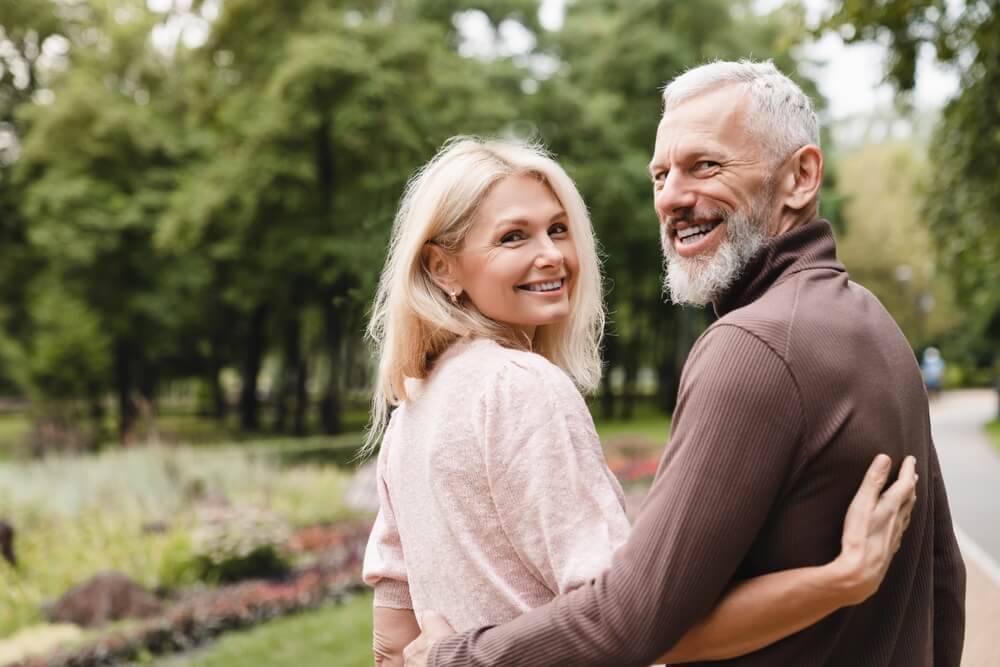 Smiling happy spouses embracing while walking in park