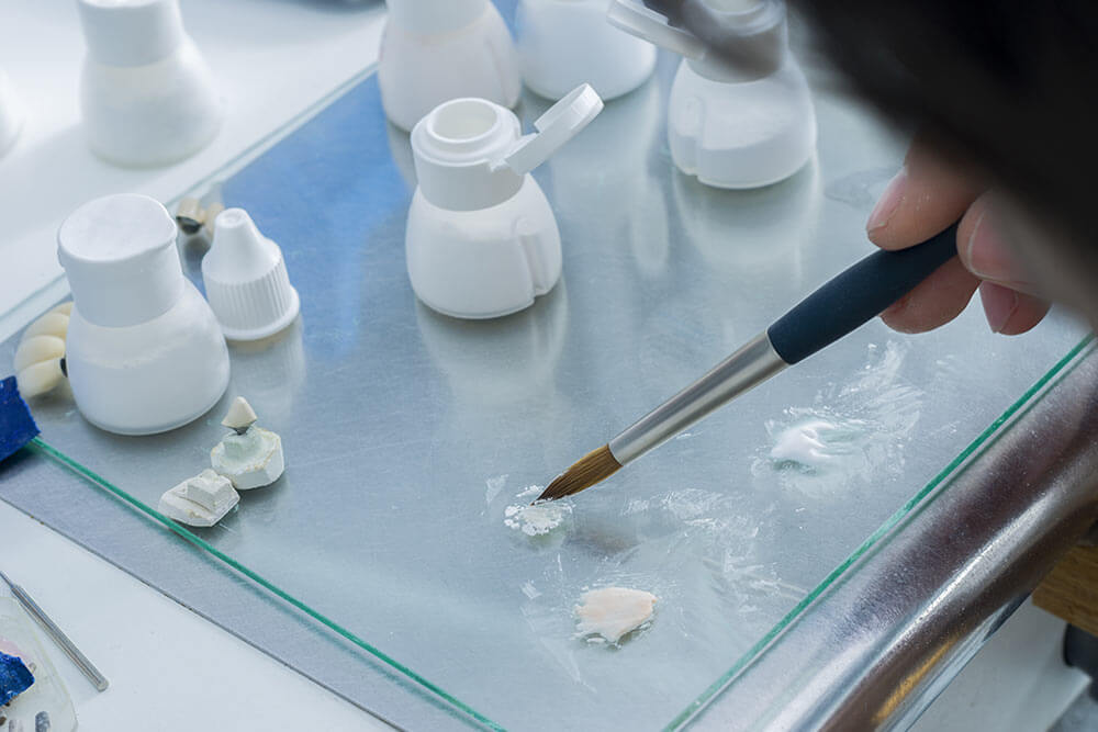 dental technician or ceramist carefully mixing ceramic powder