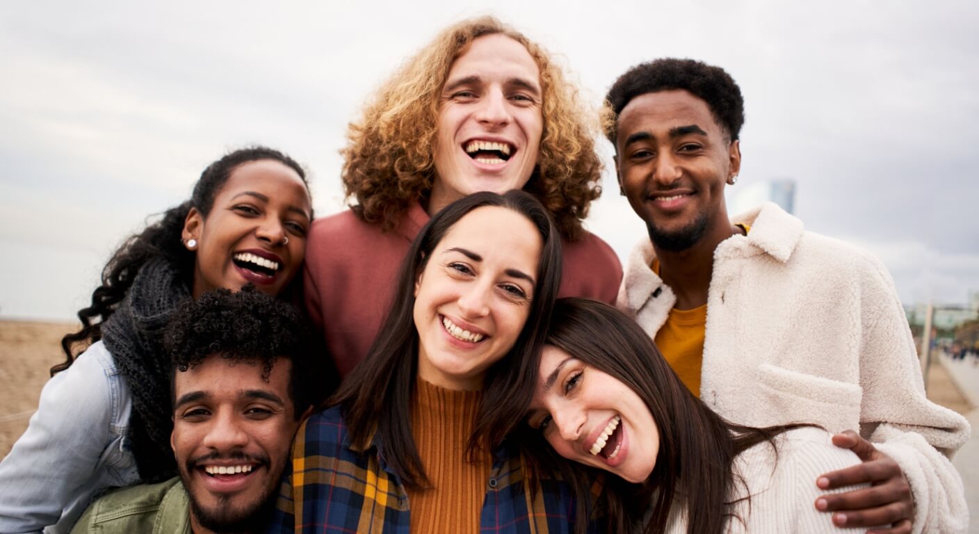 Happy friends from diverse cultures and races taking selfie outdoors.