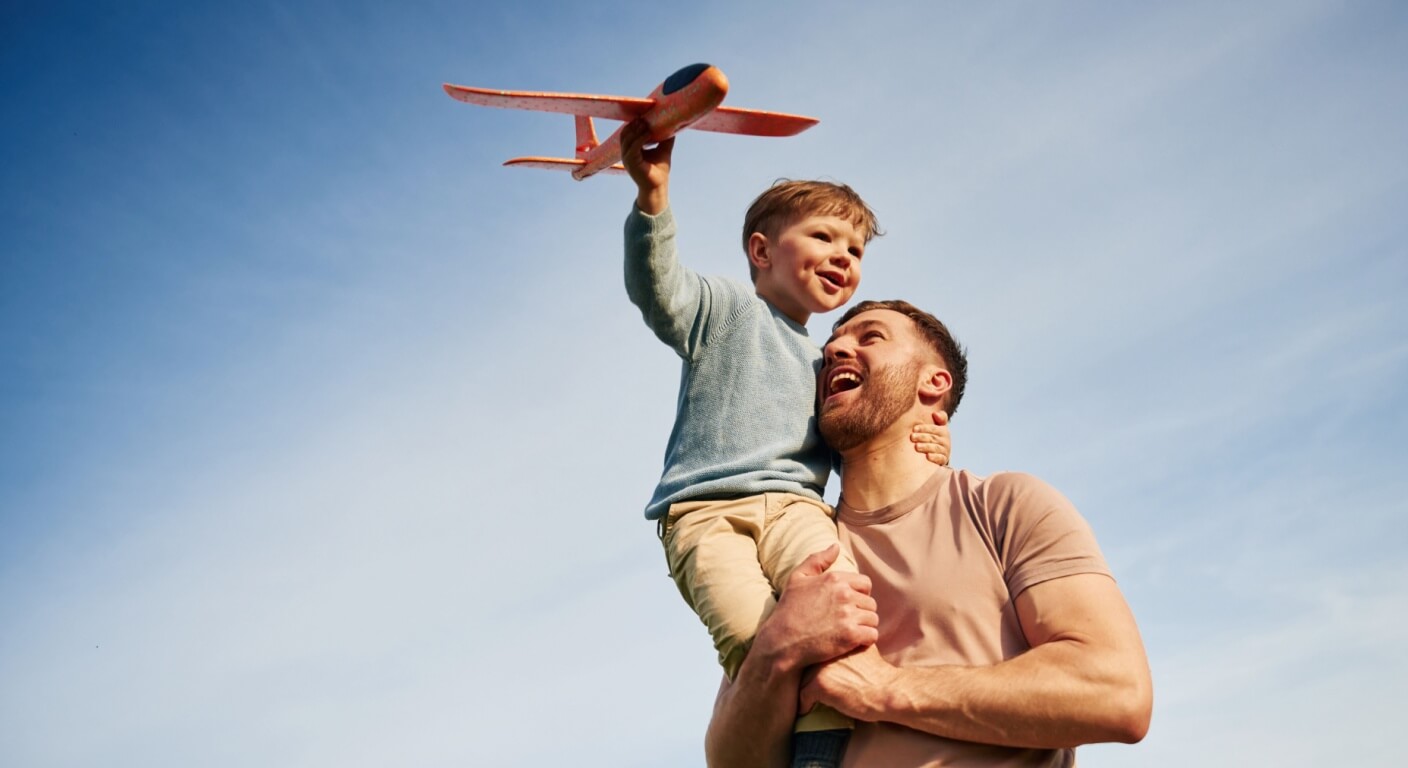Father is holding son that playing with toy plane
