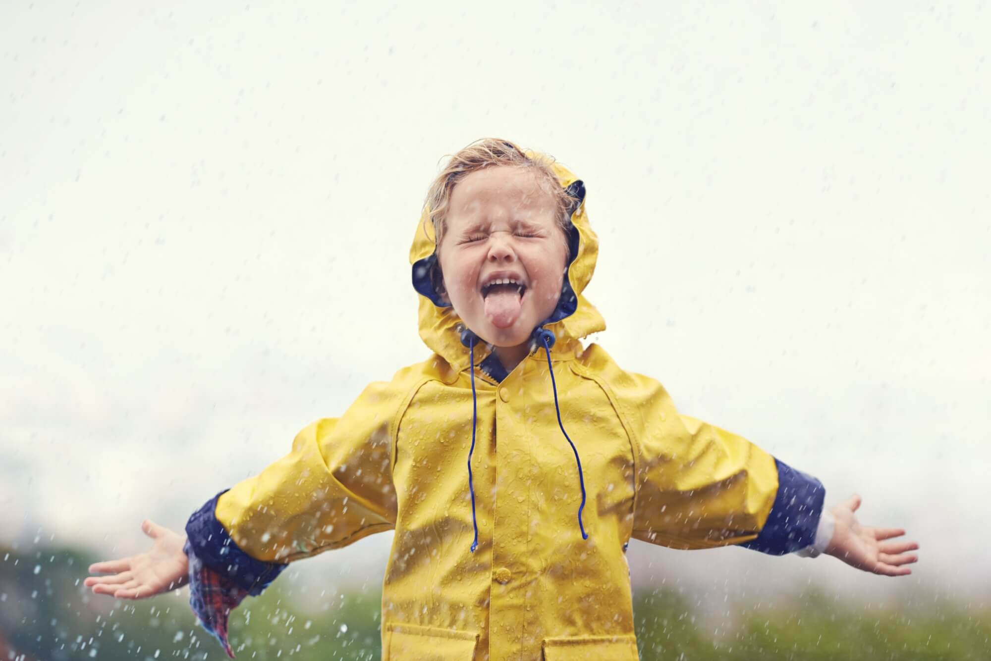 Winter, raincoat and a girl playing in the rain outdoor alone, having fun during the cold season