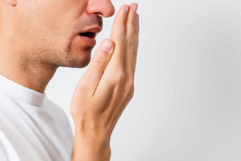 Young man checking his breath with his hand