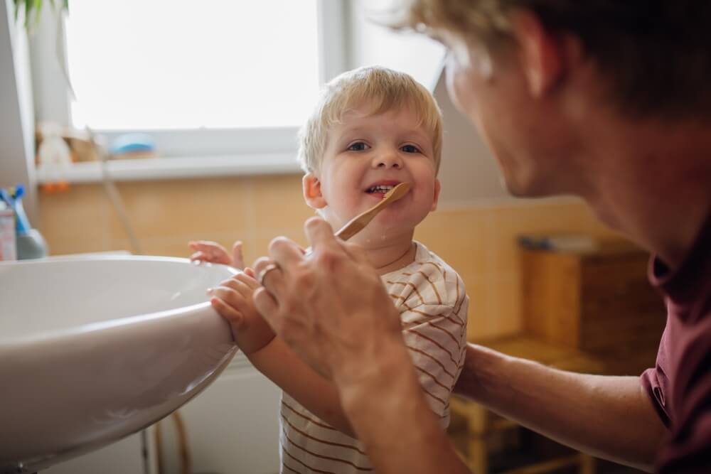 Father brushing little baby boy's teeth in the morning