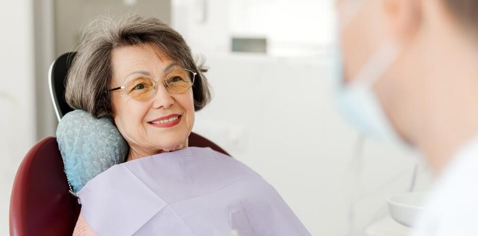 Smiling, beautiful senior woman sitting in dental chair on visit to dentist